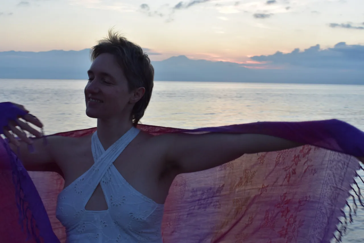 Julie Tiana enveloppée dans une étoffe face à la mer au crépuscule