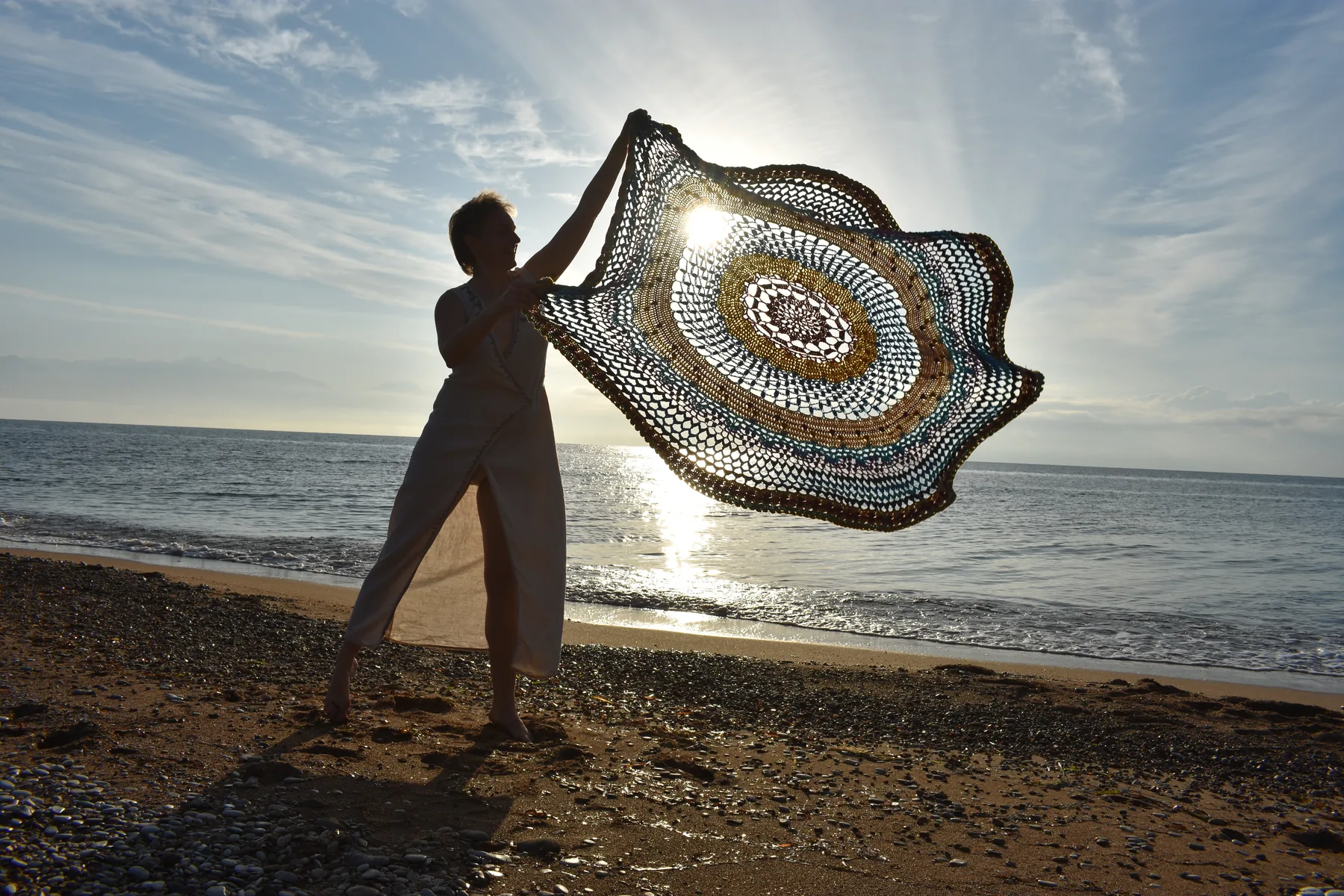 Silhouette tenant un grand mandala face à la mer